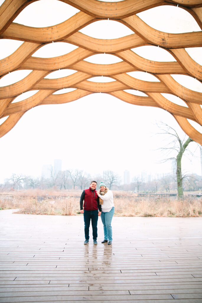 man and woman hug under the Lincoln Park Honeycomb after winter proposal in Chicago