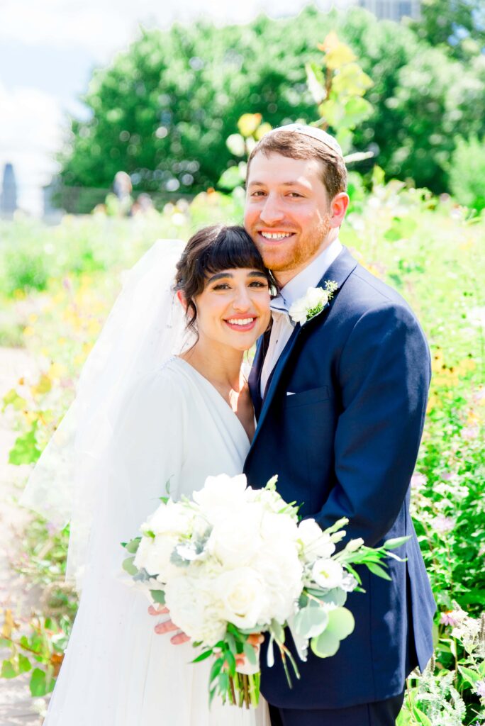 Jewish couple smiling and holding white bouquet for Lincoln Park summer wedding photos
