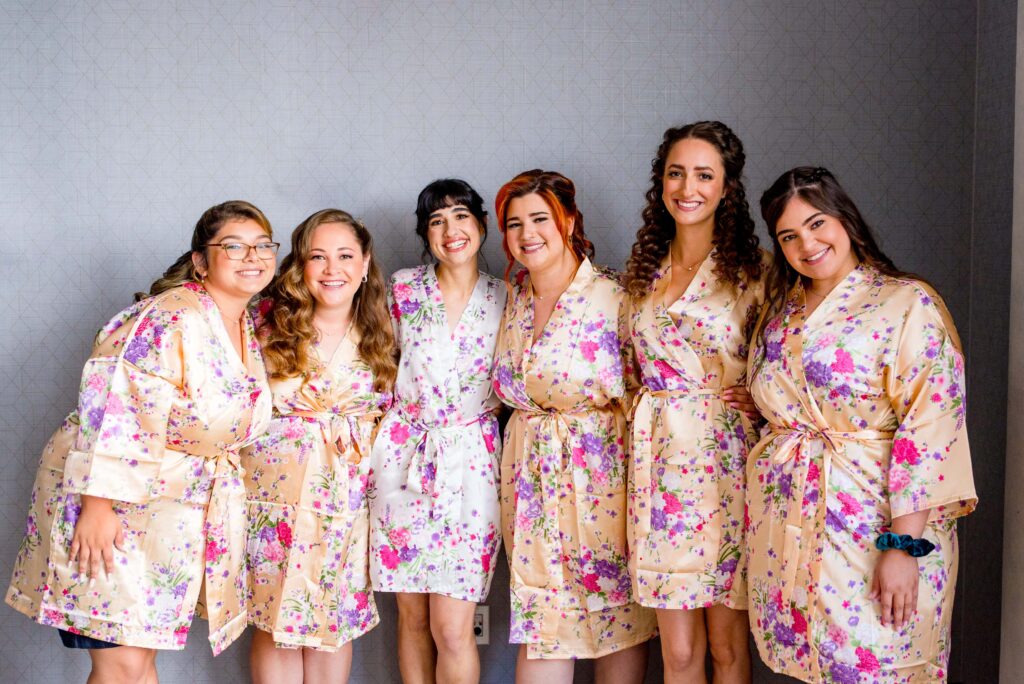 bride and bridesmaids smiling in floral peach colored silk robes