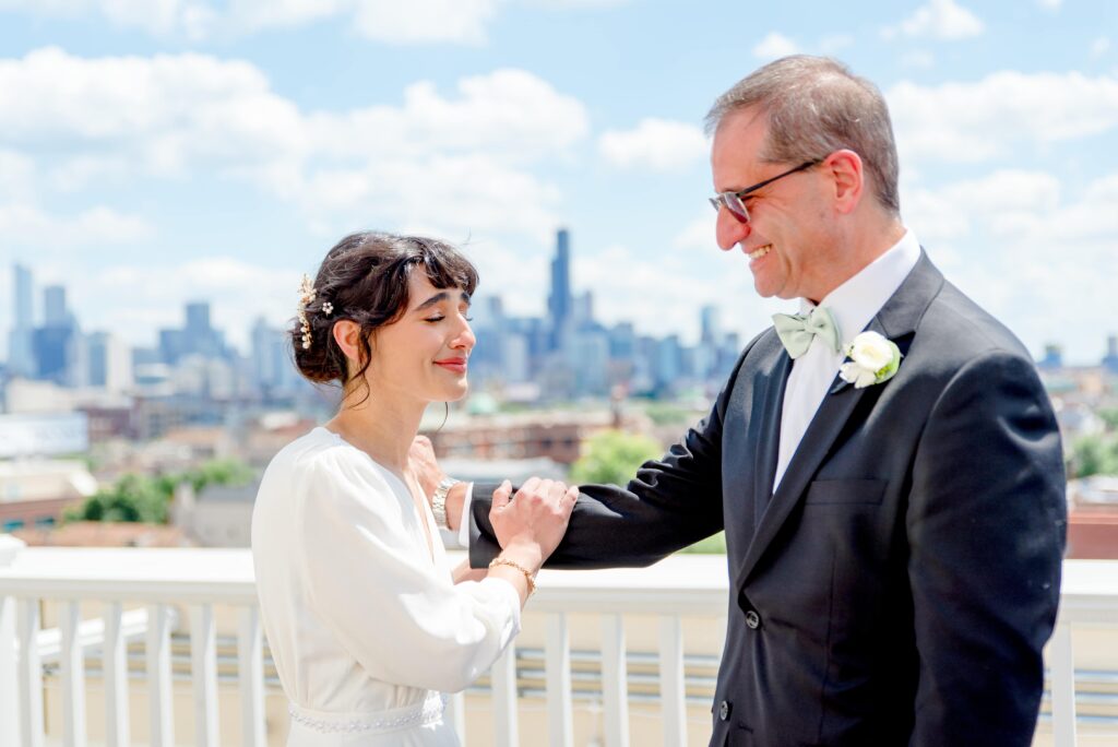 bride holding her dad's arm and smiling on the roof of Hyatt Place Wicker Park