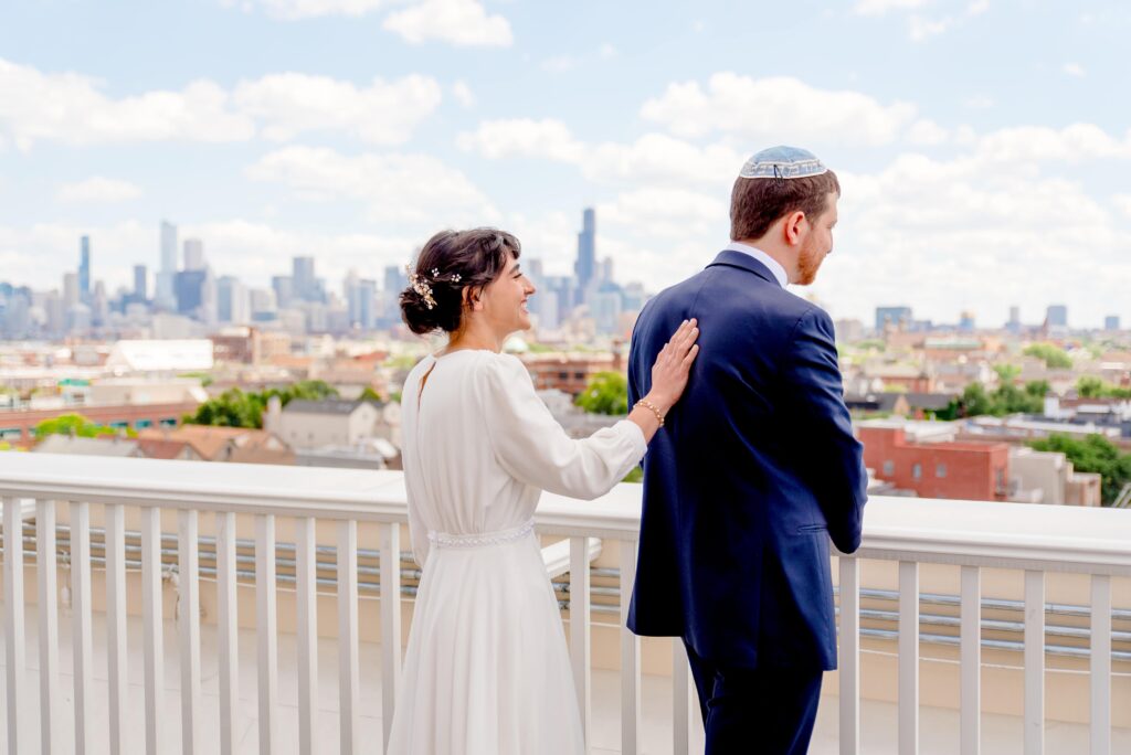 bride touching her groom on the back before a first look on the roof of Hyatt Place Wicker Park