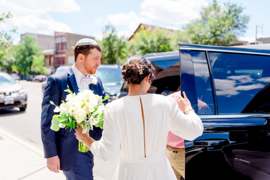 bride and groom getting into uber black on a sunny day