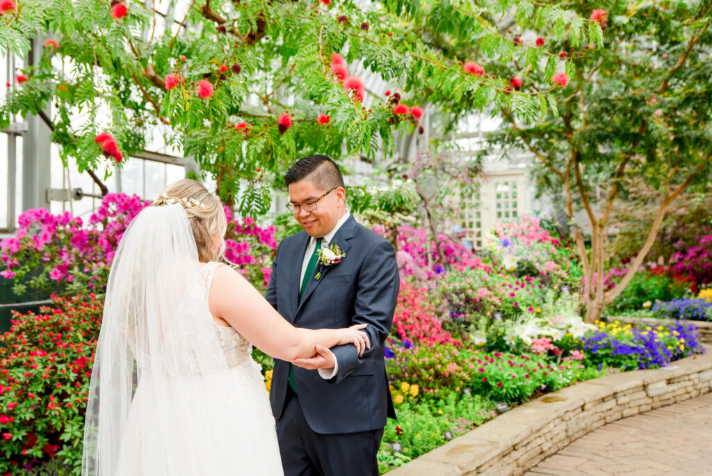 Couple's first look during their wedding at Garfield Park Conservatory in the Spring Flower Show room