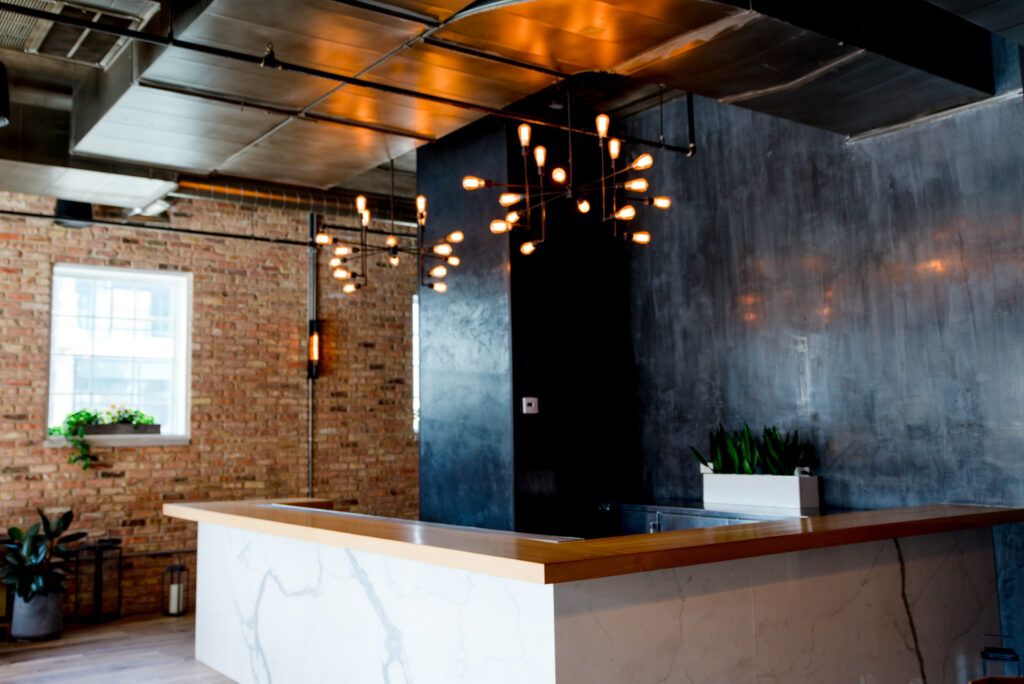 black walls and white marble bar with edison bulb chandelier at Loft Lucia