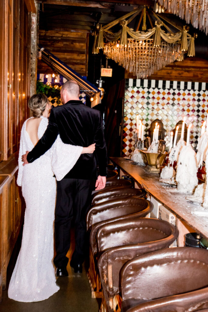 couple walking through wedding venue with warm chandeliers and fun tile walls