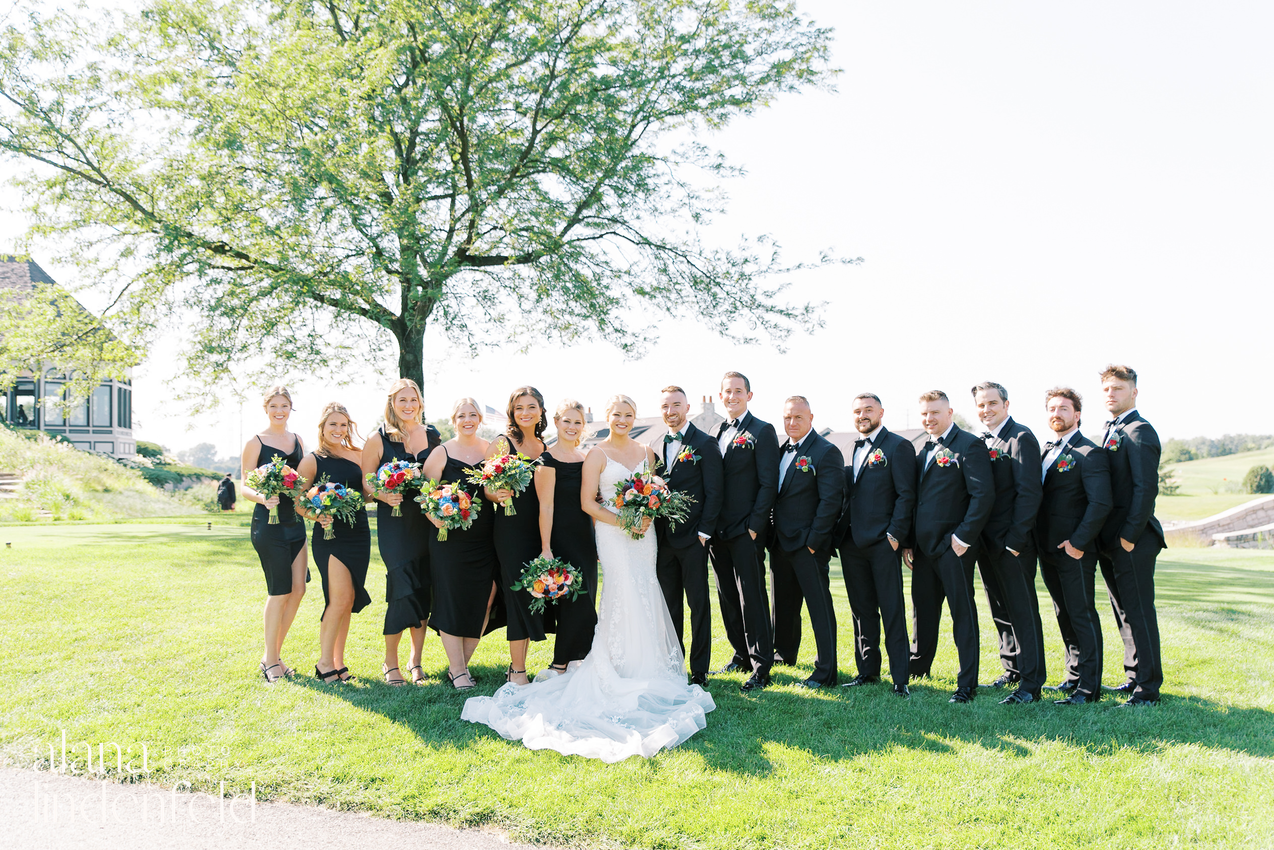 wedding party in all black with colorful flowers at Mistwood Golf Club