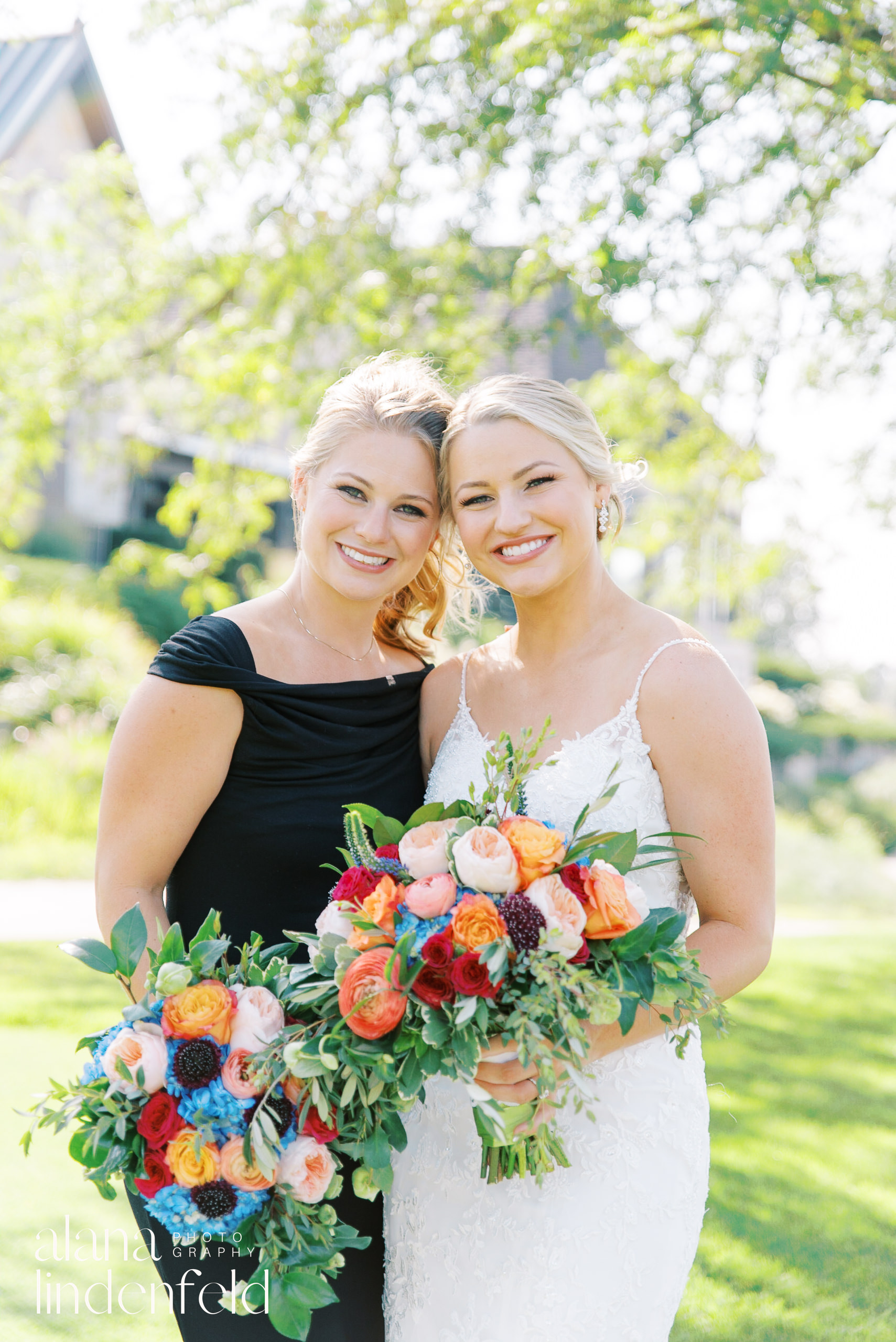 bride and braidsmaid in black dress with colorful bouquets at summer wedding