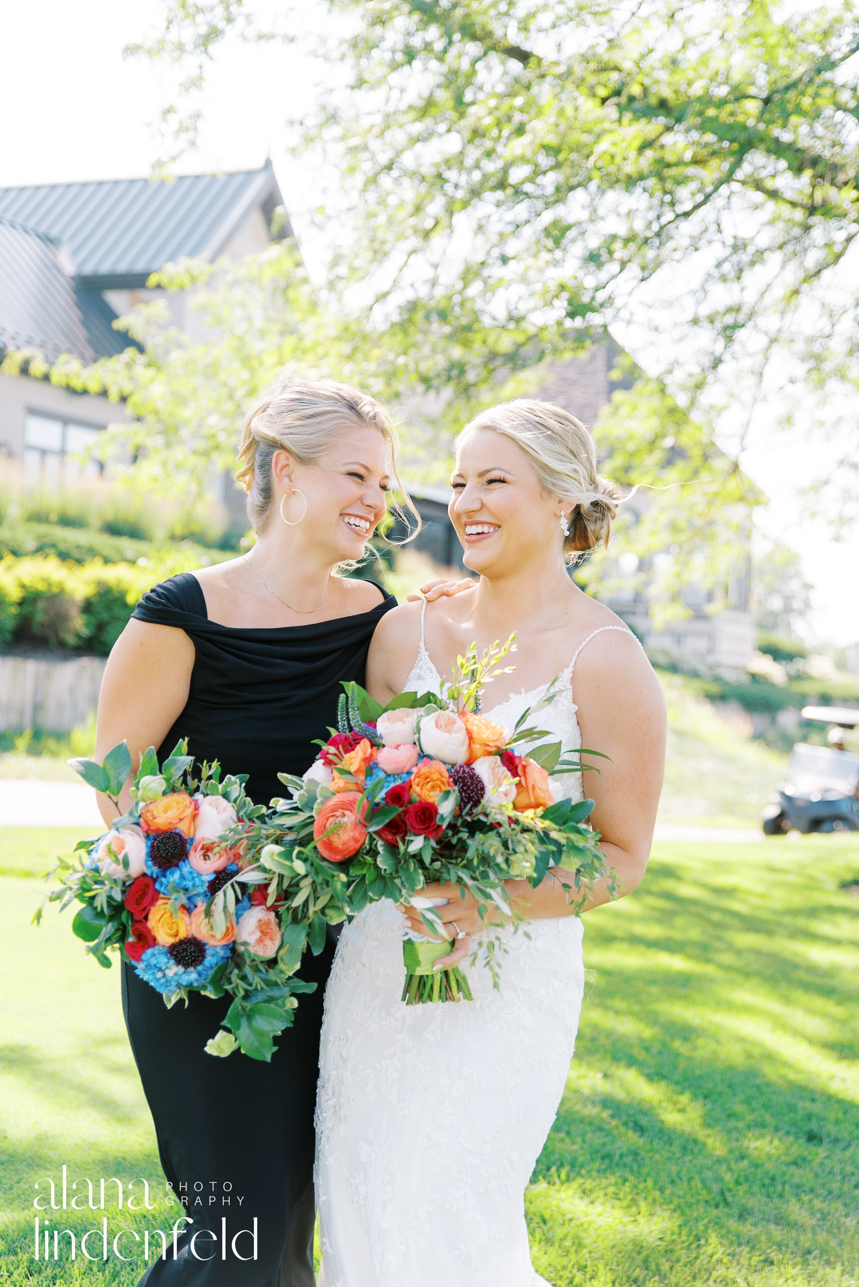 bride and bridesmaid in black dress with colorful bouquets at summer wedding