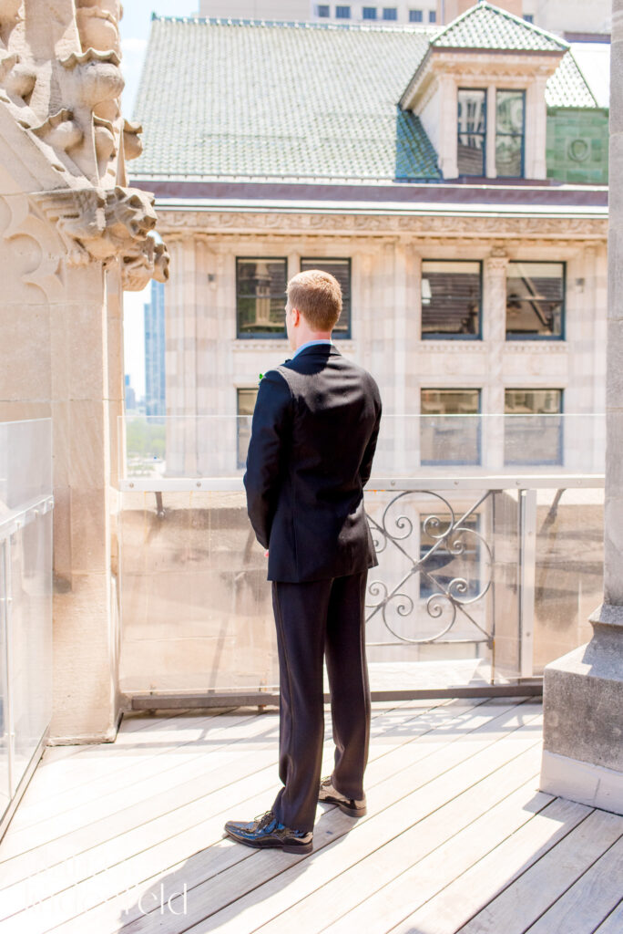 groom in black suit waiting on roof of University Club Chicago for a first look