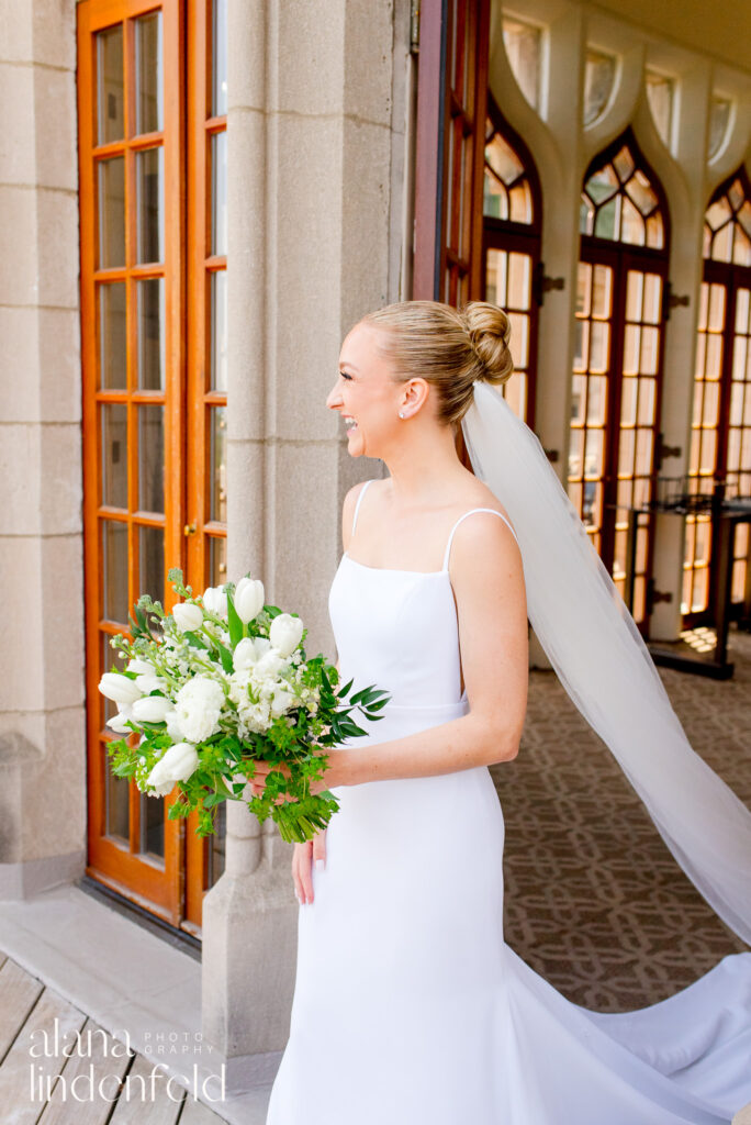 Bride with white and green bouquet smiling at University Club of Chicago 