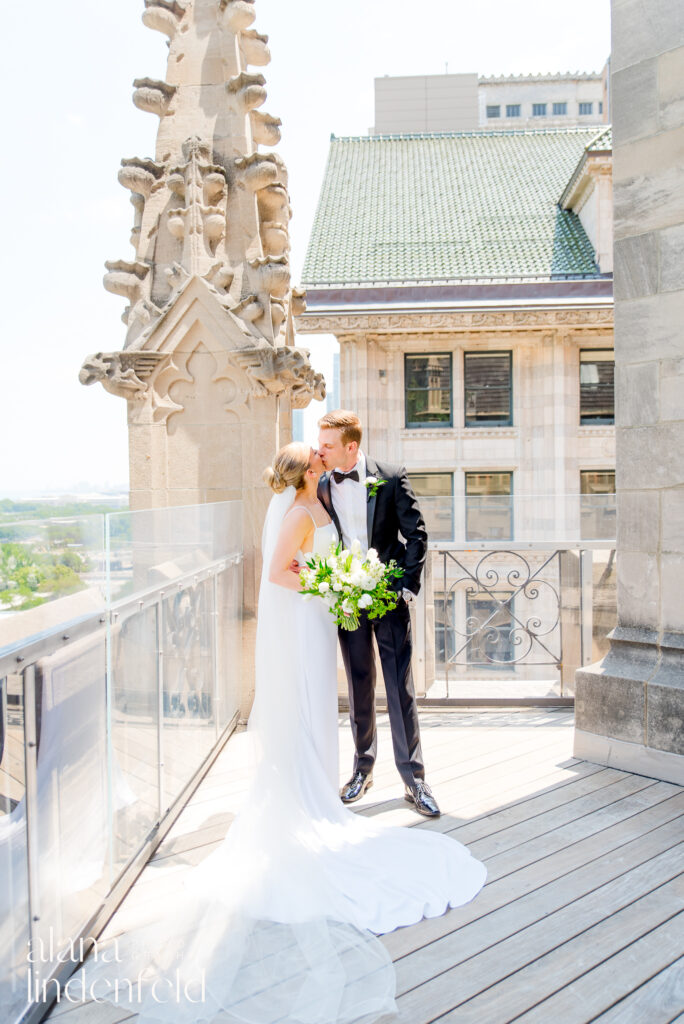 bride with long veil and groom in black suit kiss on roof of University Club of Chicago