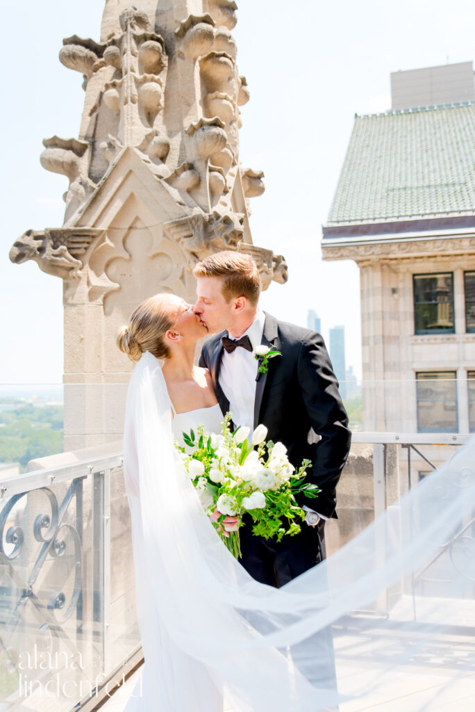 bride with long veil and groom in black suit kiss on roof of University Club of Chicago