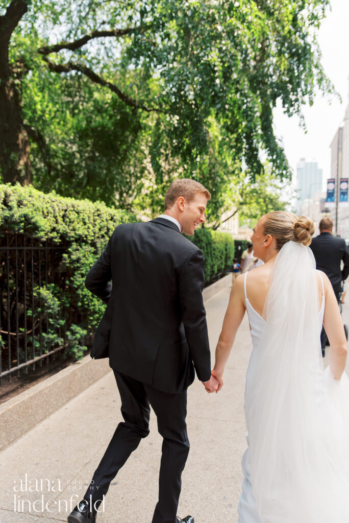 bride and groom hold hands and walk through gardens at The Art Institute of Chicago on their wedding day