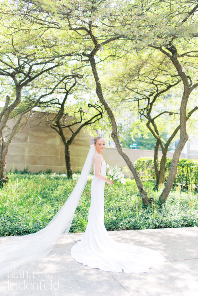 bride in simple gown and long veil in the Art Institute of Chicago gardens in the summer
