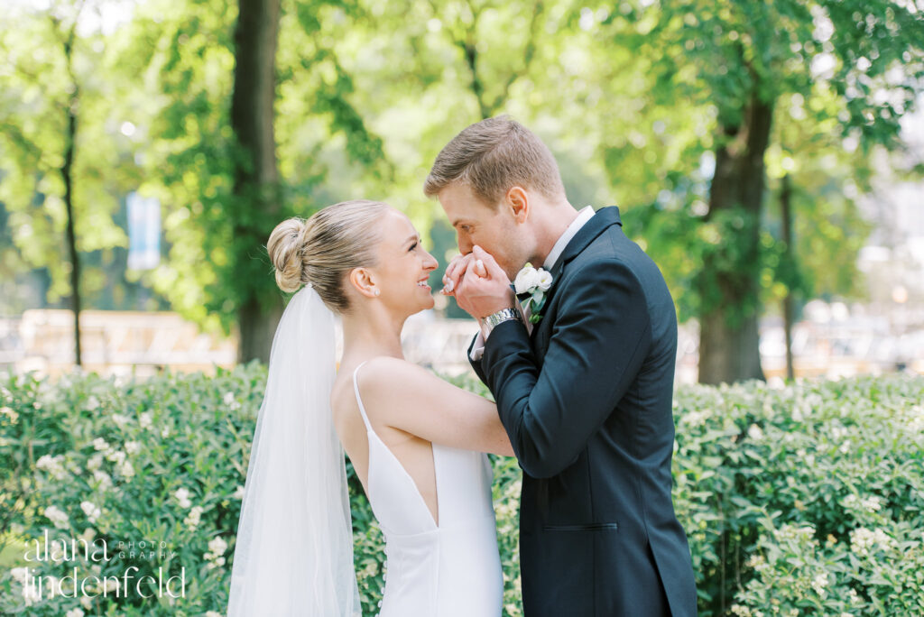 Groom kissing bride's hands in millennium Park Chicago 