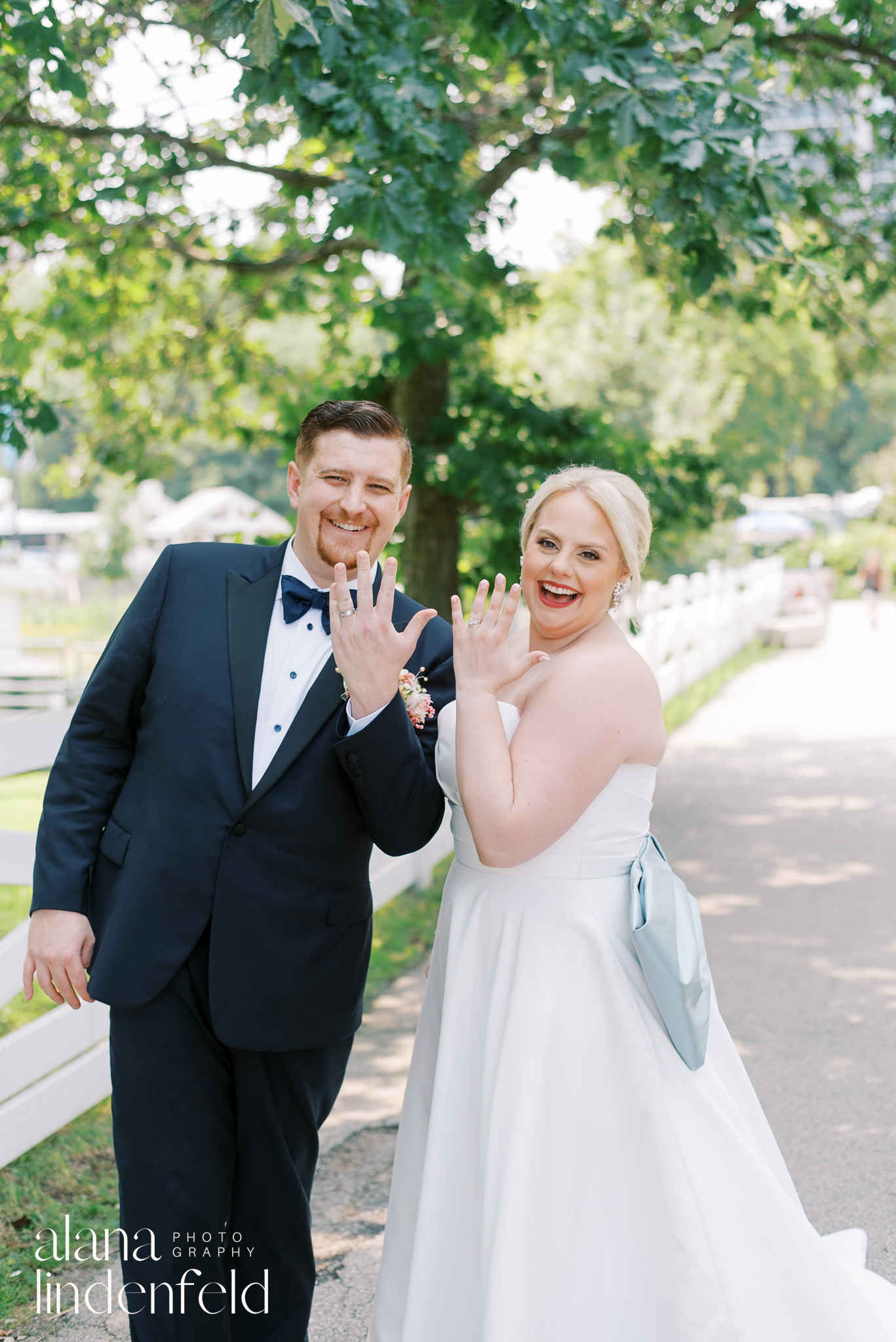 bride and groom showing off wedding rings at lincoln park in summer
