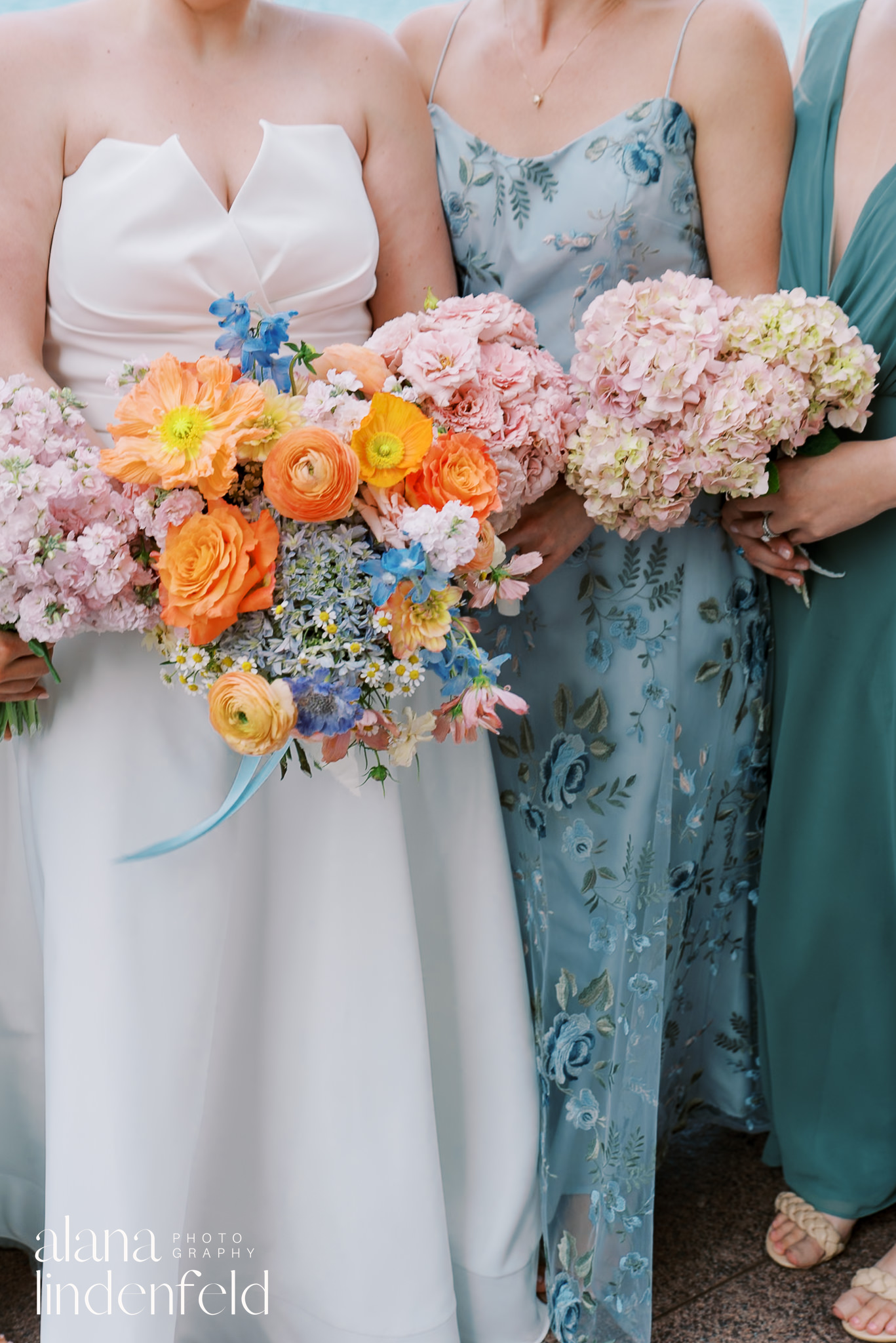 bridesmaids in blue dresses holding pink and orange bouquets 