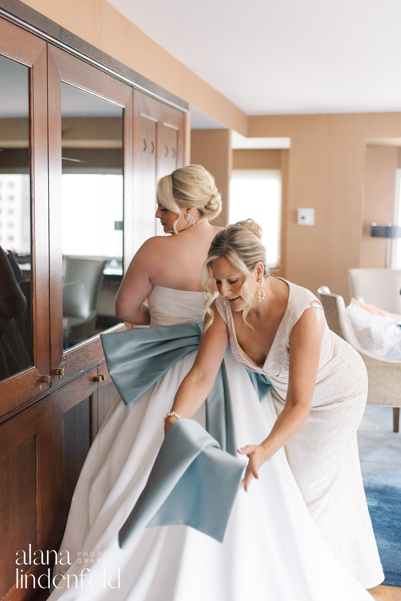 bride's mother adjusting bride's wedding dress