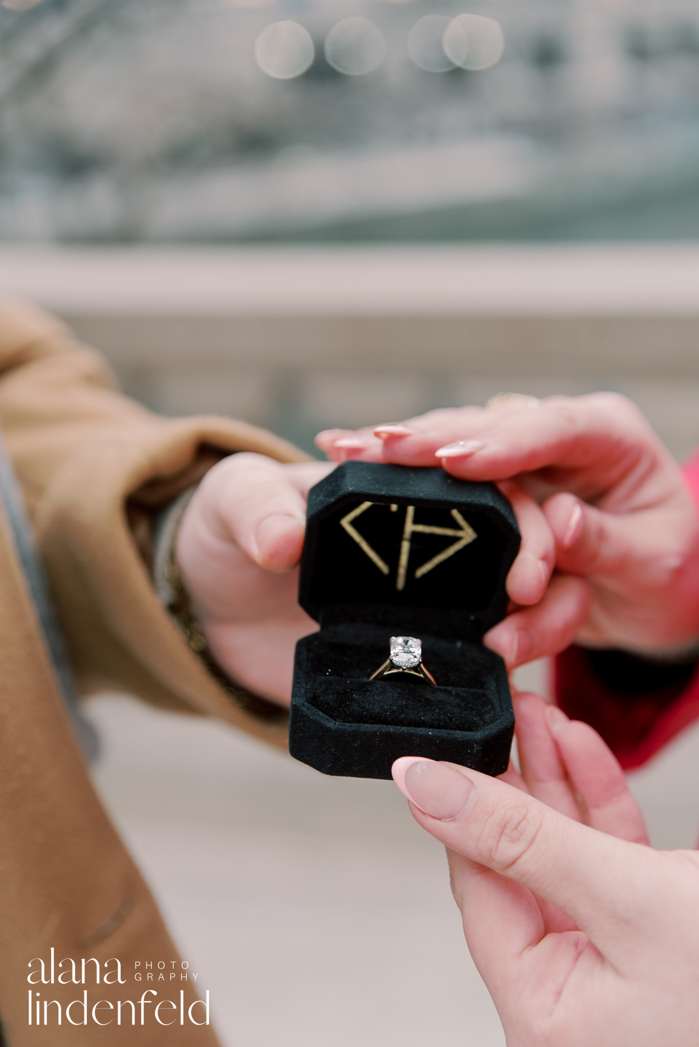 couple holding engagement ring in box