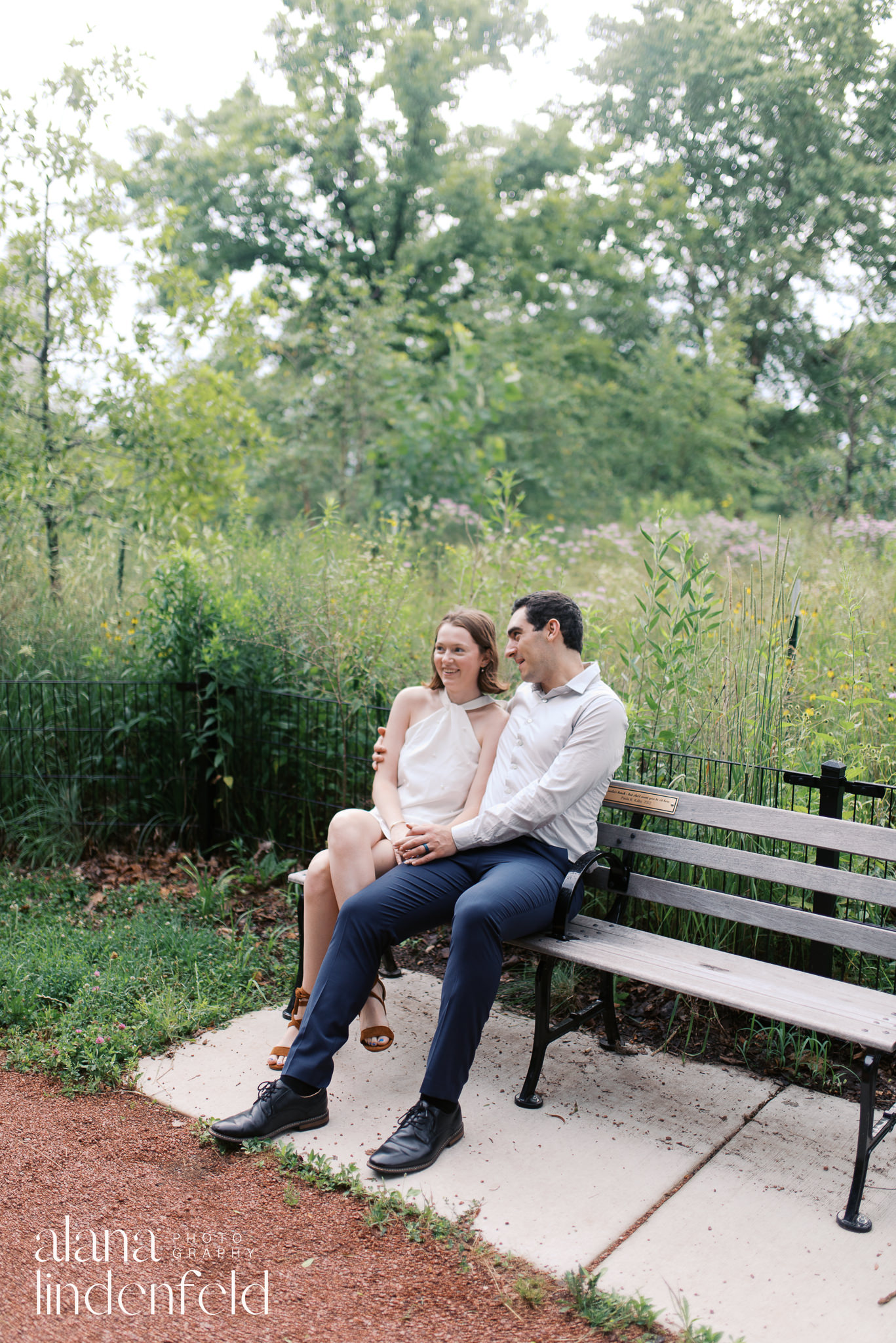 couple on a bench at North Pond in Lincoln Park for engagement pictures with wildflowers behind them