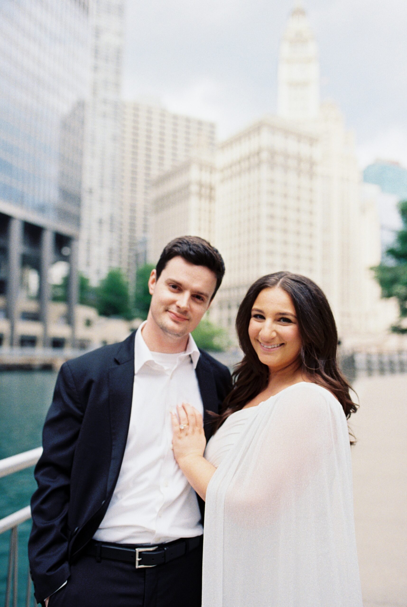 35mm film photo of couple smiling in front of Wrigley Building on Chicago Riverwalk